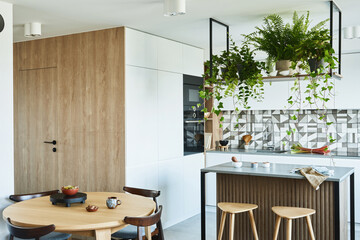 Stylish kitchen interior design with dining space. Workspace with kitchen accessories on the back ground. Creative walls with woode pannels. Minimalistic style an plant love concept.
