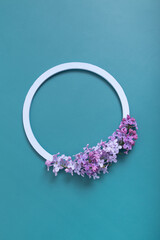 Summer or spring composition on a turquoise background. Lilac flowers with round wooden frame copy space top view. Summer, spring floral concept