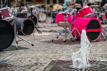 closeup of a fountain on the background of a defocused paved area with many drum kits