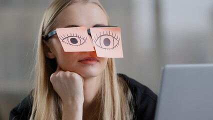 Tired female unmotivated manager with stickers on eyes sitting at desk sleeping at workplace chronic fatigue lazy businesswoman in office exhausted napping relaxing with sticky notes on eyeglasses - obrazy, fototapety, plakaty