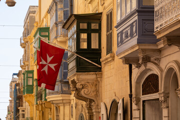 The Flag of the St John Knights with the Maltese cross hanging on a House in the City of Valetta, Malta