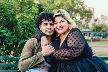 caucasian gay man and woman, friends embracing in the park smiling looking at the camera