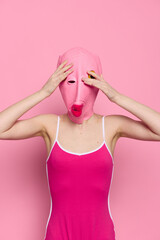 Crazy woman in pink fish head costume poses on pink studio background, provocative Halloween costume