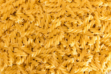 Uncooed Fusilli Pasta - Background. Texture of Bright Golden Dry Macaroni
