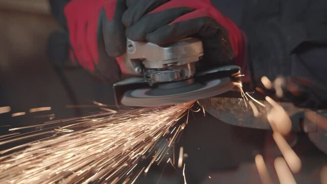 Blacksmith grinding metal plate in smithy workshop. Damascus steel knife.
