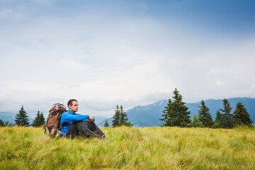 Fototapeta na wymiar Active healthy man with backpack have a rest in Alpine mountains