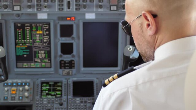 Male Pilot In Cockpit Starting Up Aircraft Avionics Instrument Panel.