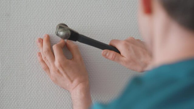 Man installing a picture hanging hook on the wall