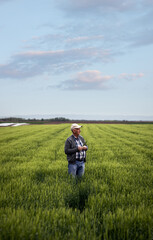 Fototapeta na wymiar Senior farmer standing in barley field examining crop.