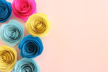 Top view image of colorful paper flowers composition over pastel pink background