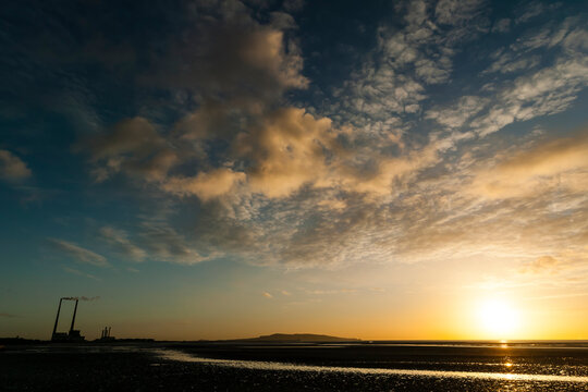 Sunrise At Low Tide With Golden Light And Thin Cirrus Clouds. Poolbeg Powerstation Chimneys. Sandymount Beach, Dublin, Ireland