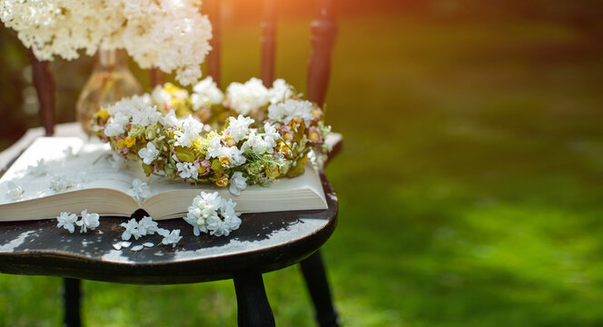 Fototapeta książka, wianek i bukiet białego bzu jako kompozycja na starym krześle w słonecznym ogrodzie