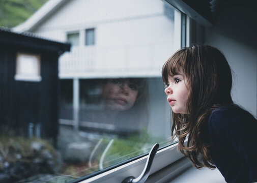 un enfant qui regarde à travers la fenêtre d'une maison