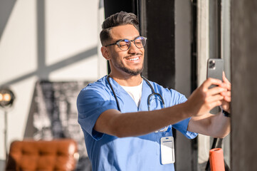 Physician with a radiant smile taking photos of himself