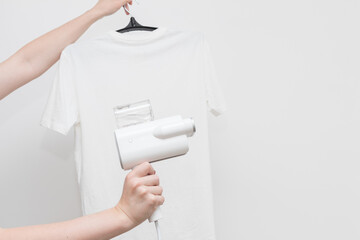 hand-held clothes steamer with white T-shirt on a light background