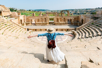 Young tourist with hat and open arms in Antique Theatre. In ancient Roman city of Jerash, Jordan