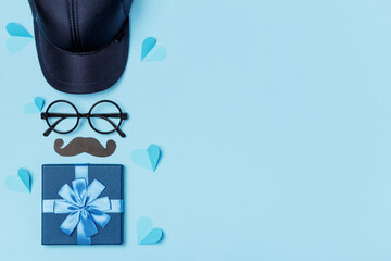 Father's day celebration concept. Gift tie glasses mustache baseball cap paper hearts on blue background