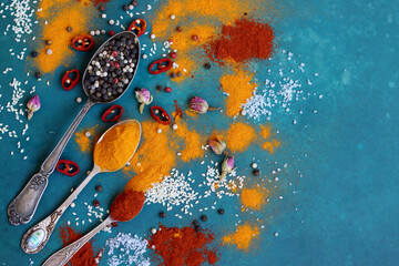 Still life with vintage silver spoons on a table. Aromatic spices and herbs on blue background....