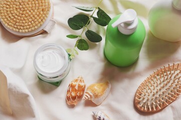 Natural herbal organic cosmetic products for skin, body and hair care top view still life photo. Massage brush, moisturizing face cream, shampoo, wooden comb and green eucalyptus leaves