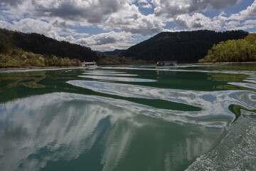 Cruise on the river Drina with reflections. The waves from the boat form beautiful shapes in the water.