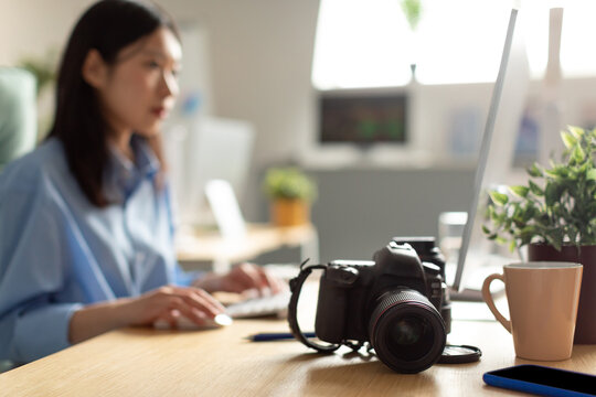 Portrait Of Asian Woman Sitting At Desk With Photo Camera