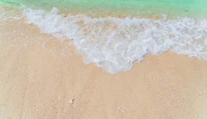 Fototapeta na wymiar Sand beach seaside with white foamy from blue sea in summer season