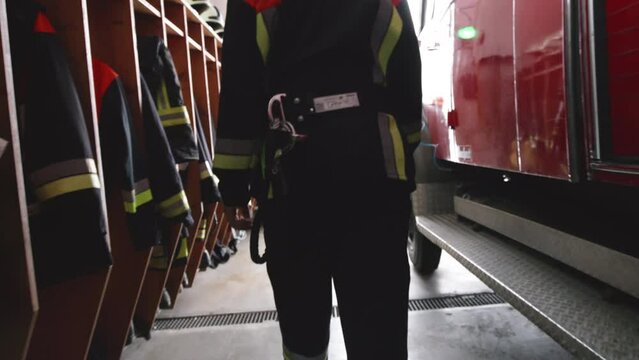 Following a Firefighter walking to a firetruck inside a fire station - handheld tilt view