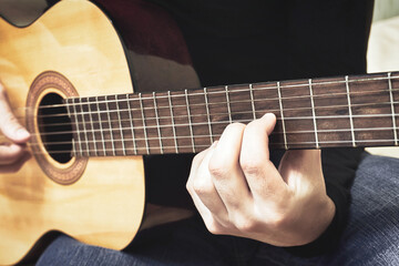 Obraz premium Close-up of a male hand on the fretboard of a classical guitar