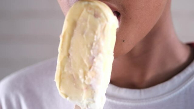 slow motion of teenage boy eating vanila flavor ice 
