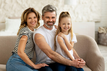 Family With Kid Showing Vaccinated Arms With Plaster At Home - obrazy, fototapety, plakaty