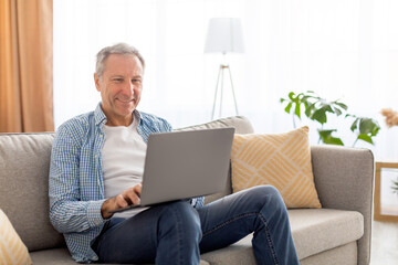 Confident casual mature using laptop at home