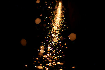 Sparks in dark. Flow of sparks from metal processing. Lights on black background. Work in workshop....