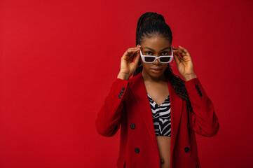 Fashionable Black woman wearing classic red suit with double breasted blazer, zebra print top,...