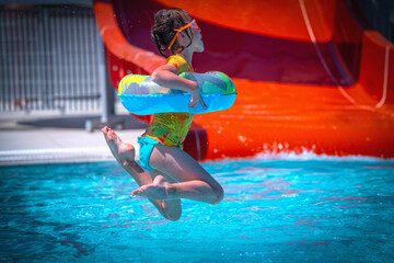 Happiness and summer holiday concept. Young child girl jumping into the swimming pool.