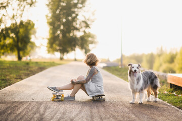 Cute girl woman rides skateboard, dog Australian Shepherd breed runs with owner, generation z,...