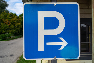 Blue square sign with p letter and a right arrow at a parking lot for cars
