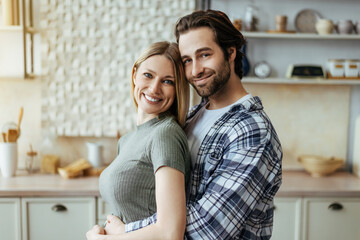 Smiling handsome european millennial guy with stubble hugs blond lady and enjoy tender moment at...