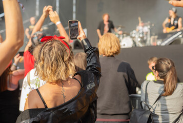 A young girl filming with her cell phone at a music festival