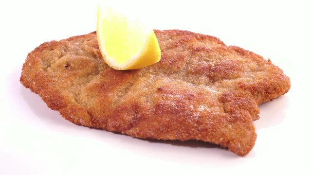 Wiener Schnitzel mit Zitrone paniert auf wei&szlig;em Hintergrund - Drehteller