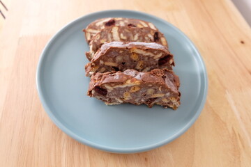Homemade mosaic chocolate biscuit cake served in a blue plate, selective focus. It is called 