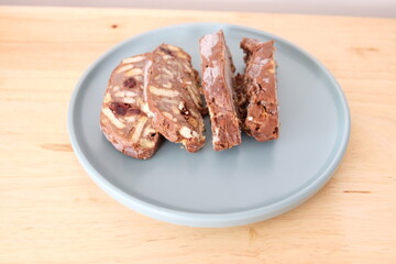 Homemade mosaic chocolate biscuit cake served in a blue plate, selective focus. It is called 