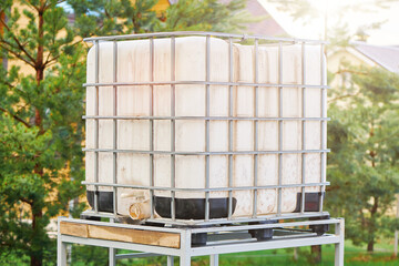 White square water tank on metal frame installed on the backyard for watering the garden. White...