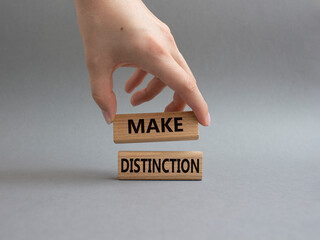 Make distinction symbol. Concept words make distinction on wooden blocks. Beautiful grey background. Businessman hand. Business and make distinction concept. Copy space.