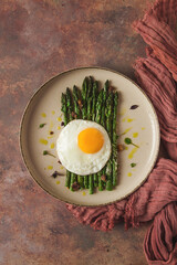grilled asparagus, with fried egg, spices and herbs, parmesan cheese, on a beige plate, top view, rustic, no people