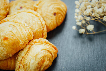 Curry puff pastry in a stone plate placed on a wooden table.