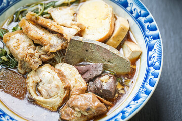 Rolled Rice Noodles in Five-spices Broth served in a tiled cup on a  wooden table.
