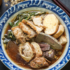 Rolled Rice Noodles in Five-spices Broth served in a tiled cup on a  wooden table.

