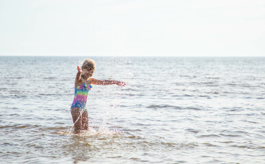 Girl of European appearance having fun in water on the beach and splashing