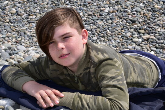 Boy lying on a pebble beach close-up