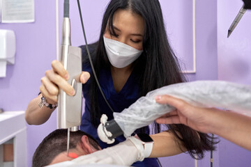 Doctor of a clinic applying laser to a patient to perform a beauty skin treatment